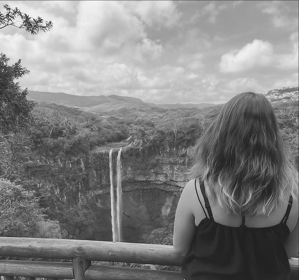 Sara, de espaldas, contempla una cascada entre montañas